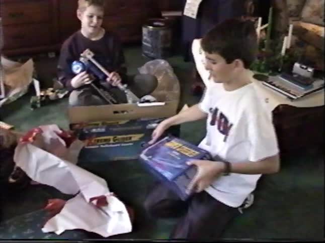 Vintage home movie captures two brothers excitedly unwrapping toys on Christmas morning in the 1990s