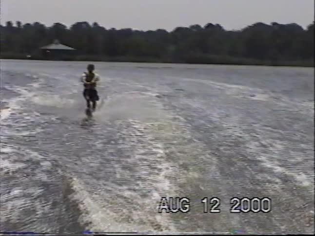 Vintage home movie from the year 2000 shows a young boy successfully getting up on one water ski on a calm lake