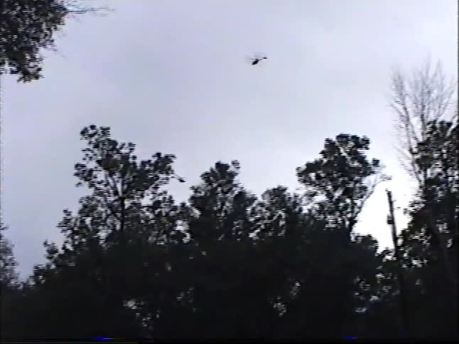 Two young boys play with their new remote control toy helicopters in a field, launching them high into the sky in this vintage 2000 home video