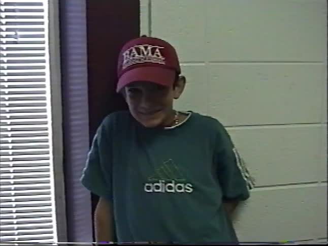 Vintage home movie footage captures boys posing for the camera in a community hall in the 1990s