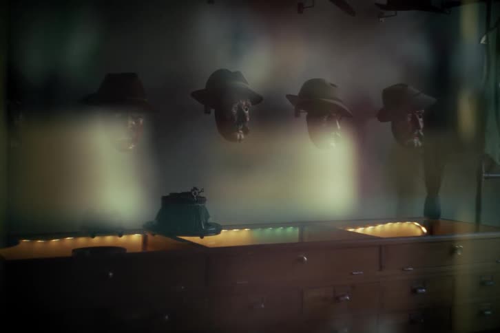Four floating heads wearing vintage fedoras are showcased in a mysterious, dimly lit shop window display