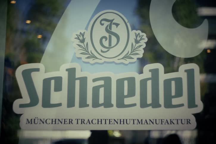 A close-up of a vintage logo for a traditional German hat maker on a shop window in Munich