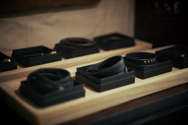 Close-up rack focus shot of various handcrafted leather bracelets sitting in display boxes on a wooden tray