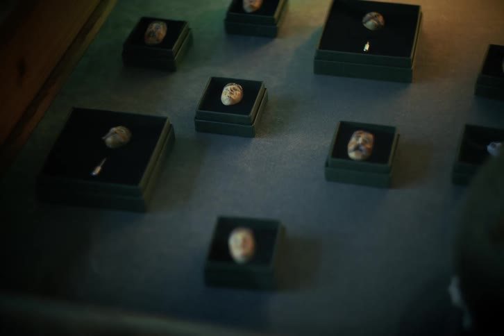 Rack focus shot of a peculiar collection of miniature carved human heads in a dimly lit exhibit