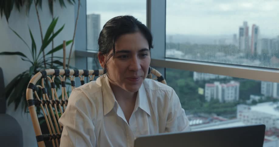 Businesswoman sitting in a chair in front of her laptop has an expression of relief and happiness