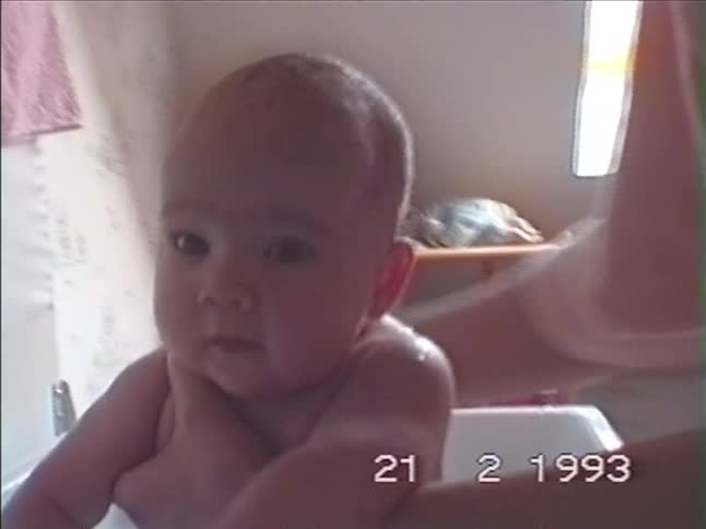 Close-up home video from 1993 of an adorable baby being held and washed in a bathtub