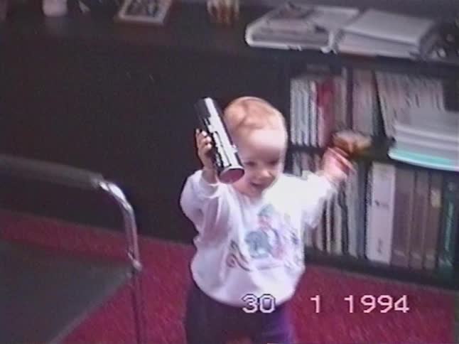 Vintage home movie from 1994 shows a curious toddler reaching up to a shelf, grabbing a can, and proudly showing it off