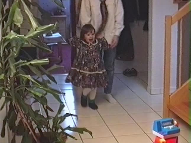 A little girl is led by her parent into a room and reacts with pure joy and excitement to her new toy grocery store, captured on vintage 1993 home video
