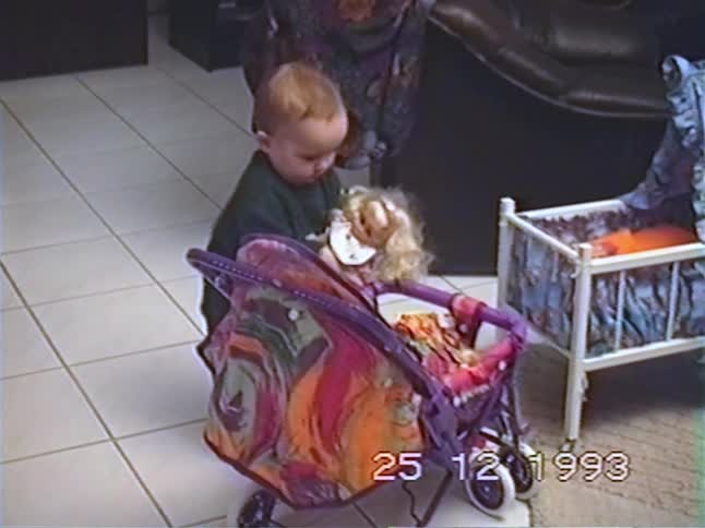 Authentic 1993 VHS footage of a cute toddler playing with a new doll and stroller by the Christmas tree