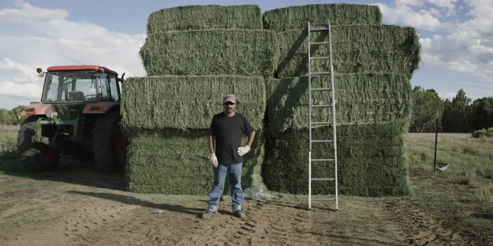 Man stands in front of large hay bales