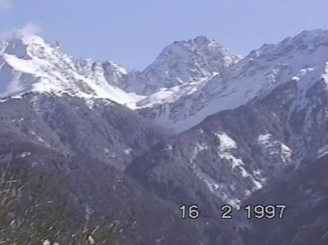 Vintage VHS footage from 1997 pans across a majestic, snow-covered mountain range on a clear winter day