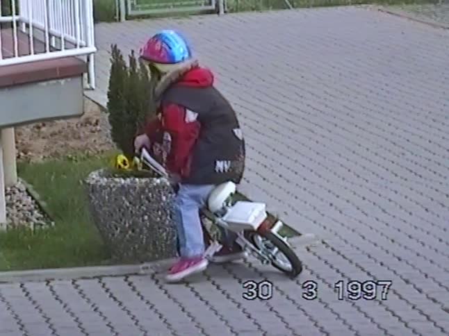 Vintage home video from 1997 shows a little kid in a helmet learning to ride their first bicycle