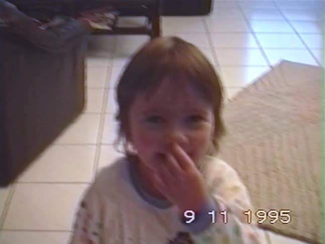 A cute toddler smiles sweetly at the camera before picking her nose in a funny home video from 1995