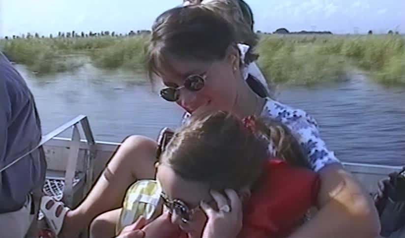 A mother holds her scared daughter on her lap during a thrilling airboat ride through a swamp in this vintage home video