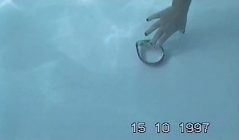 A watch sinks to the bottom of a pool in a vintage underwater home video from 1997 featuring a young girl with goggles