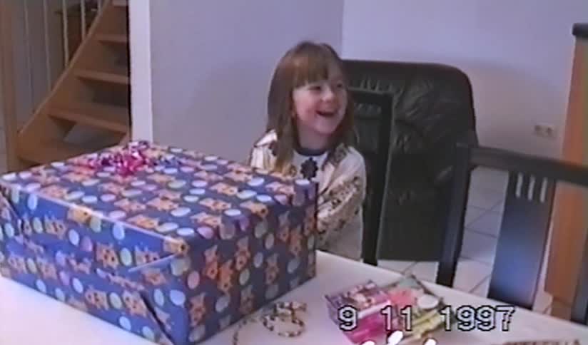 A cute young girl excitedly unwraps a huge birthday present in this authentic 1997 home video