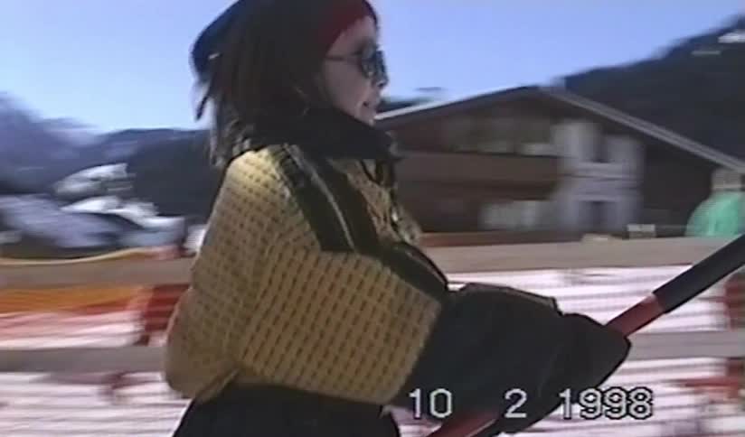 A young girl smiles while being pulled up a snowy mountain on a surface ski lift in this vintage 1998 footage