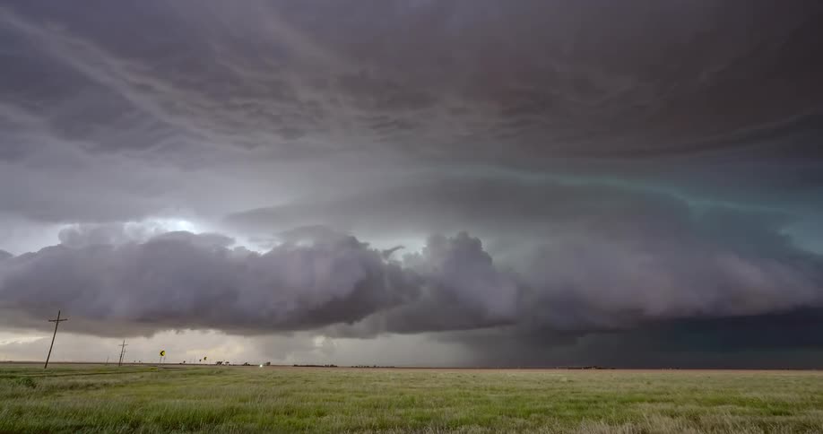 A dramatic time-lapse captures a massive supercell thunderstorm churning and rotating over a wide-open grassy plain