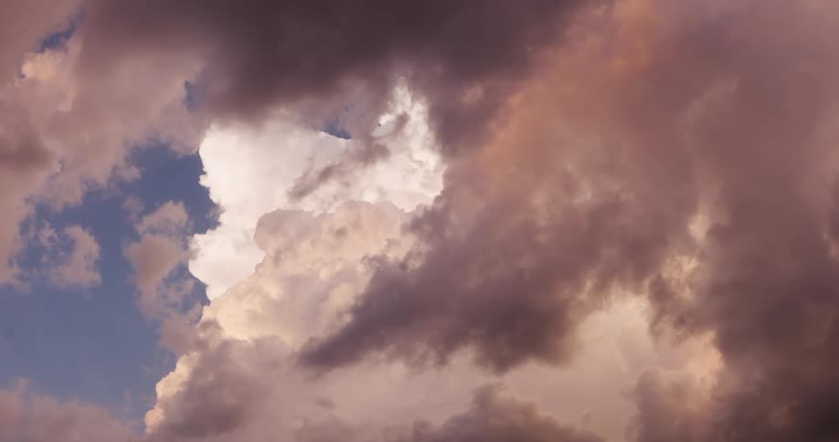 A majestic view of dramatic pink and grey clouds gathering in the sky at dusk