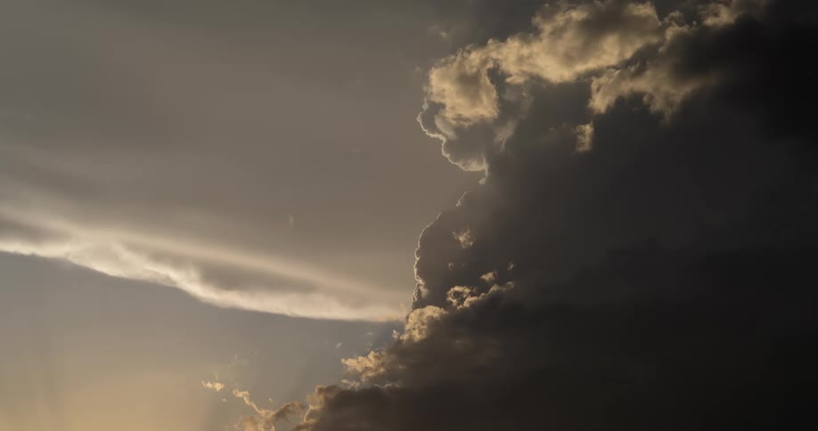 An awe-inspiring view of dark, billowing clouds with sunlit edges against a hazy sky