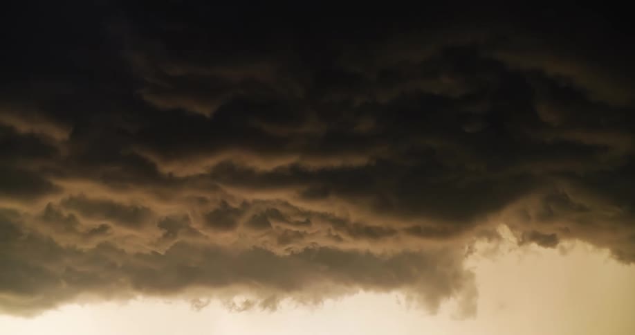 Ominous dark storm clouds billow and churn in a moody, foreboding sky