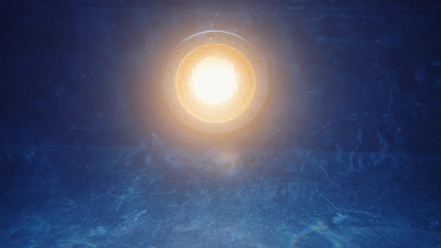 An underwater pool light glows with a warm yellow hue in the dark blue water, with caustic reflections dancing below