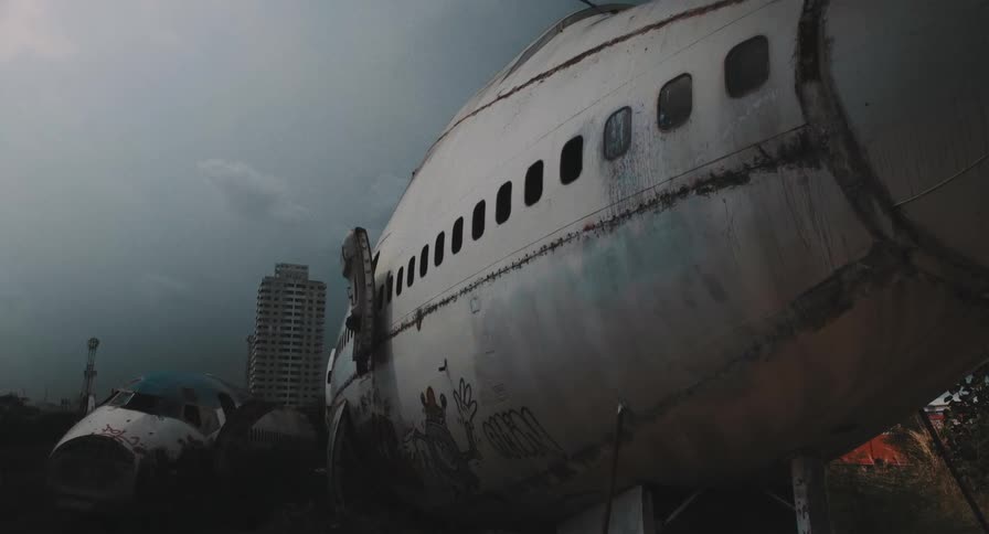 A figure in a protective suit explores an abandoned airplane graveyard under a dark and stormy sky in a post-apocalyptic cinemagraph