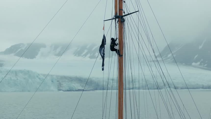 A sailor bravely climbs the tall wooden mast of a schooner sailing through the frigid arctic waters in front of a massive glacier