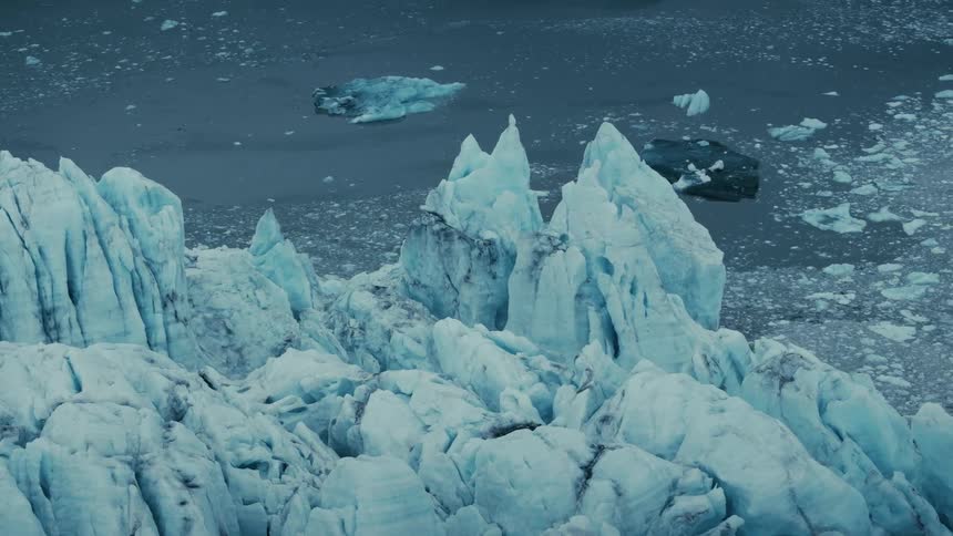 High-angle view of jagged blue ice peaks on a massive glacier by the frigid arctic sea
