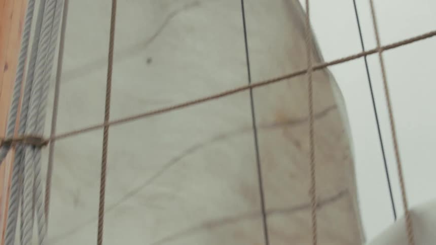 Close-up of a tall ship's sail billowing in the wind next to the wooden mast