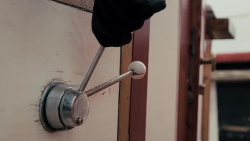 A close-up shot of a gloved hand pushing a vintage mechanical lever with a white knob