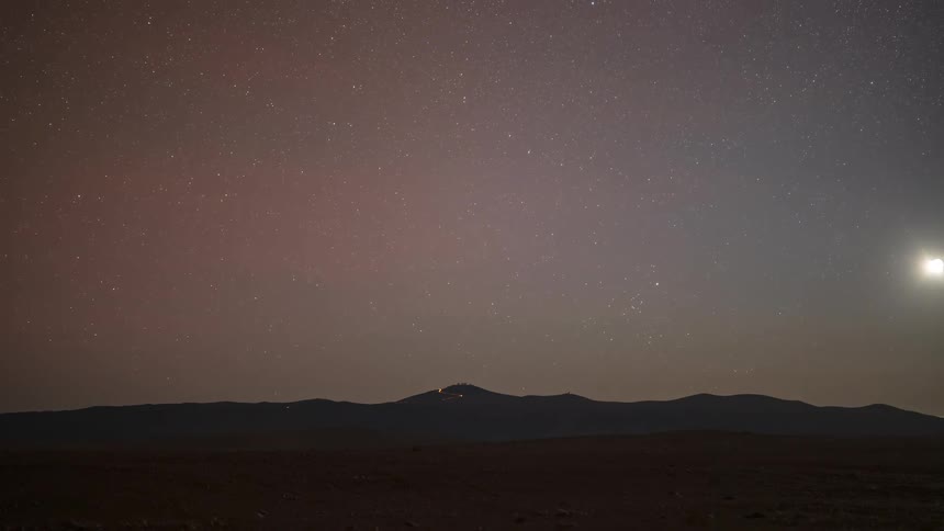 A gorgeous holy grail time-lapse captures the transition from a vibrant sunset to a star-filled night sky with the Milky Way over silhouetted mountains