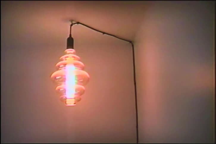 An ornate, decorative glass light bulb turns on, illuminating the corner of a room in a vintage-style clip