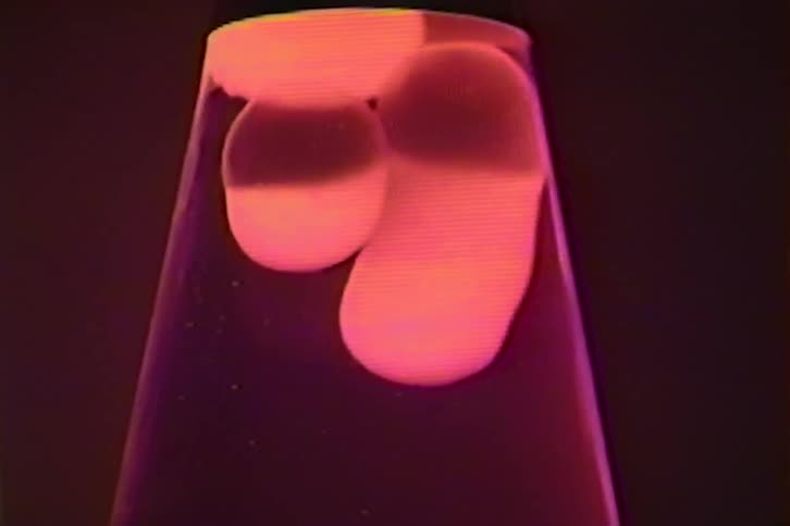 Hypnotic motion of glowing red wax blobs rising and falling inside a classic retro lava lamp from the 1980s