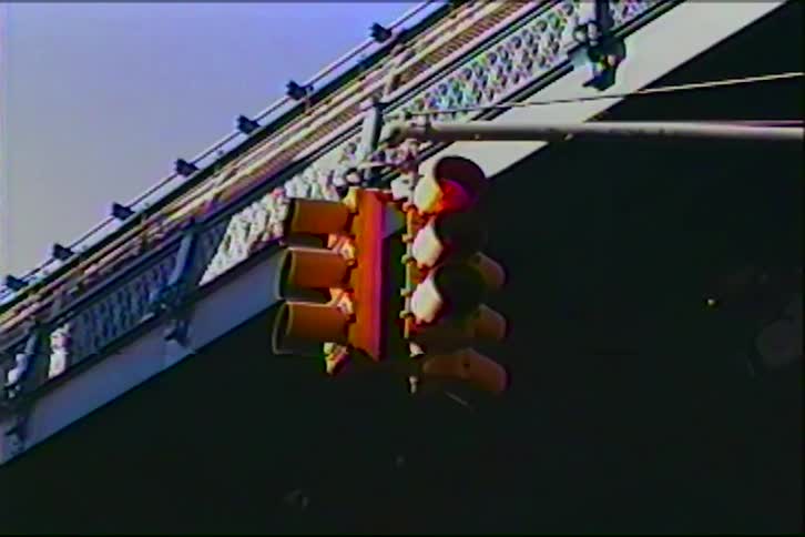 A slow zoom on a city traffic light under a bridge on vintage VHS tape