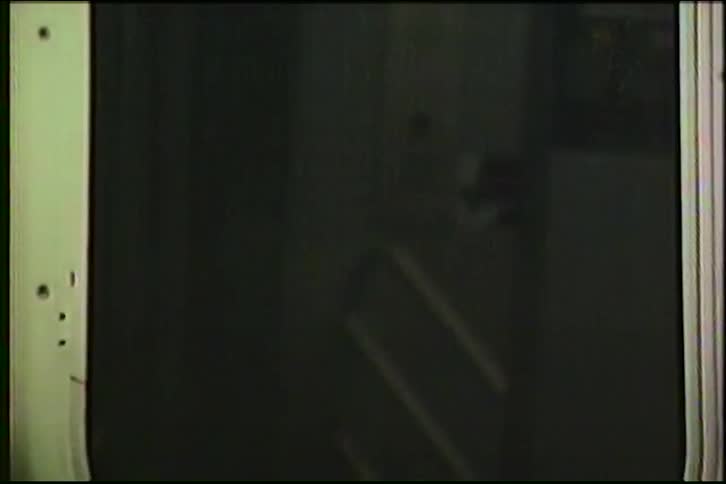 A gritty, dark, point-of-view shot from a moving New York City subway car window as it speeds through a tunnel