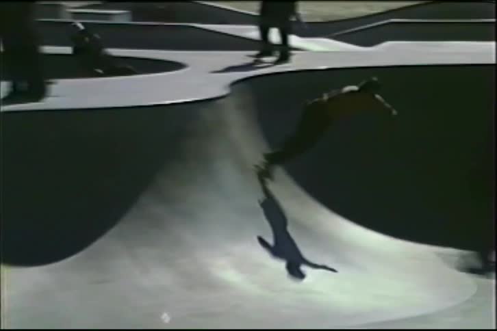 Vintage VHS footage captures several men skateboarding in a concrete skatepark bowl on a sunny day