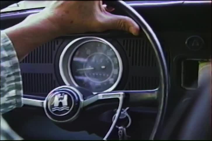 Close-up shot from the 1970s of a driver's hand on the steering wheel of a classic Volkswagen Beetle