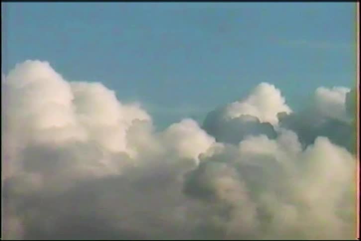 A serene, still shot of fluffy white and gray clouds against a calm blue sky