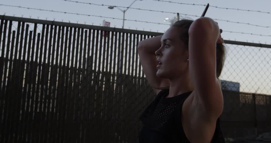 Woman rests standing in front of a barbed wire fence