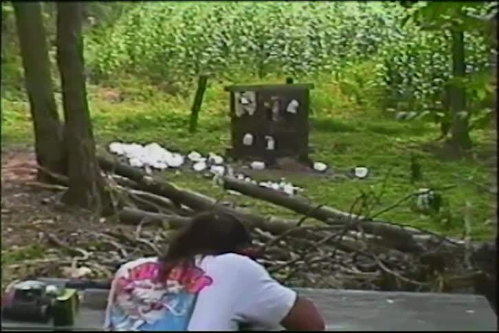 Slow-motion vintage footage captures a person shooting a target with a rifle, causing it to explode in a dramatic cloud of white powder