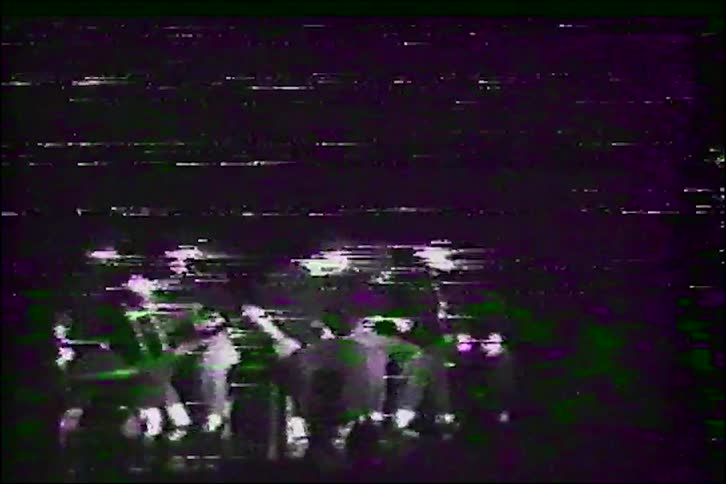 Vintage VHS footage of a band performing on stage with heavy glitch and distortion effects
