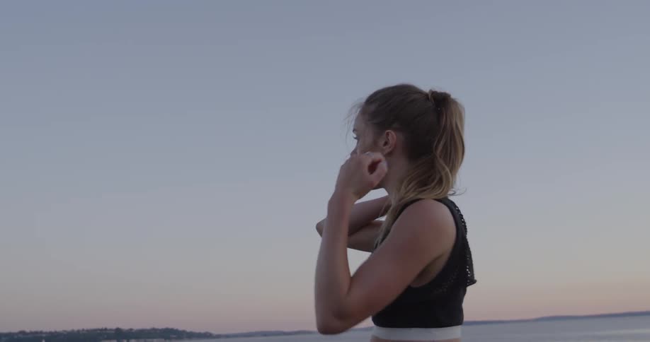 A woman stands lakeside in a sports bra