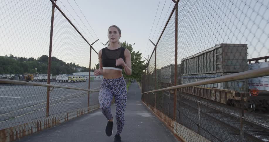 A woman jogs through rusty chain link fences