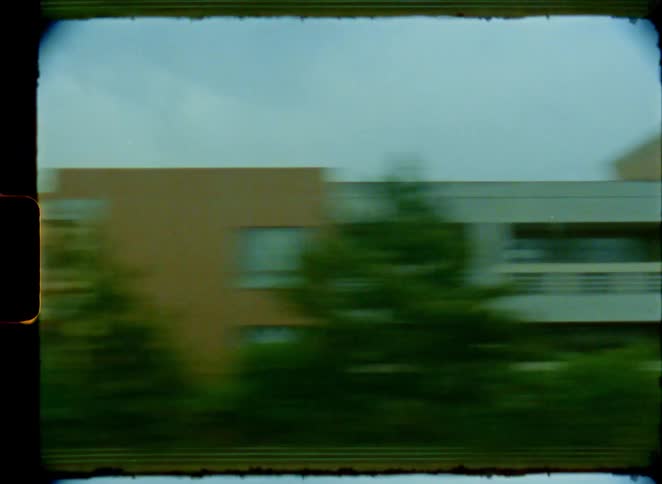 Vintage Super 8 footage captures a blurry, high-speed drive along a coastal highway on an overcast day