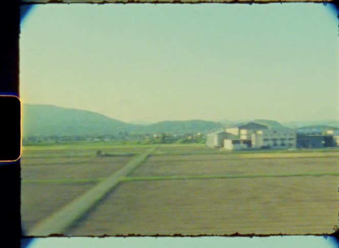 Vintage 8mm footage captures a scenic journey by train through the Japanese countryside, with views of mountains and rice paddies