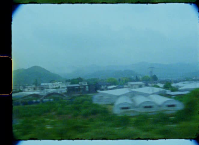 Dreamy vintage 8mm footage captures the hazy rural landscape of Japan as seen from a moving train window