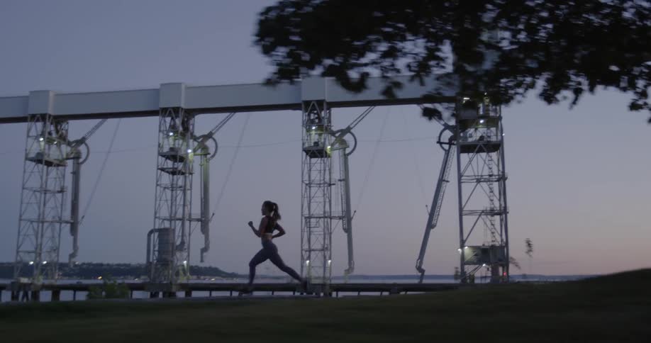 A woman is jogging on a path near a harbor