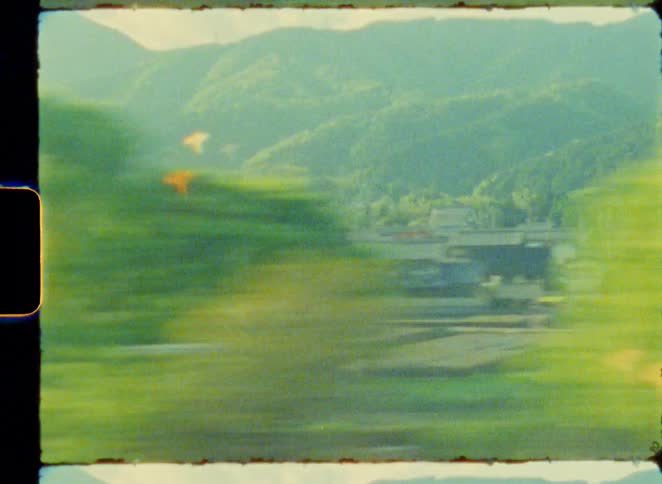 Dreamy vintage 8mm film footage captures the blurry, scenic Japanese countryside from a moving train window