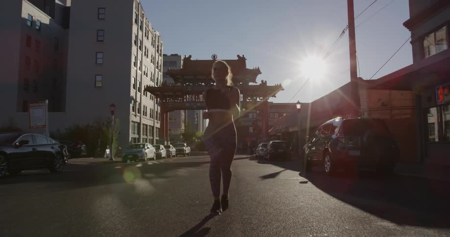 A woman is jogging in the streets past a building